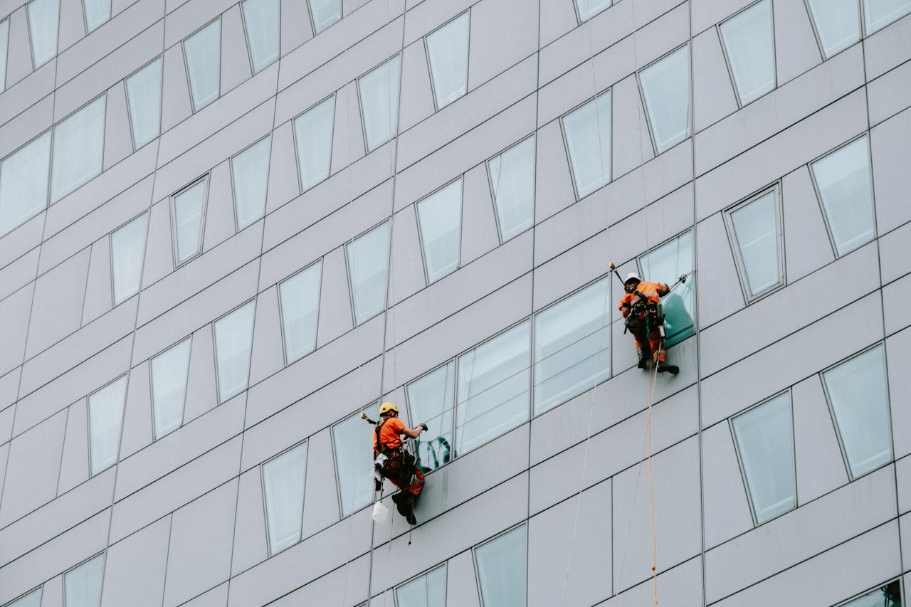 Home High-rise window washers in safety gear cleaning a skyscraper facade.
